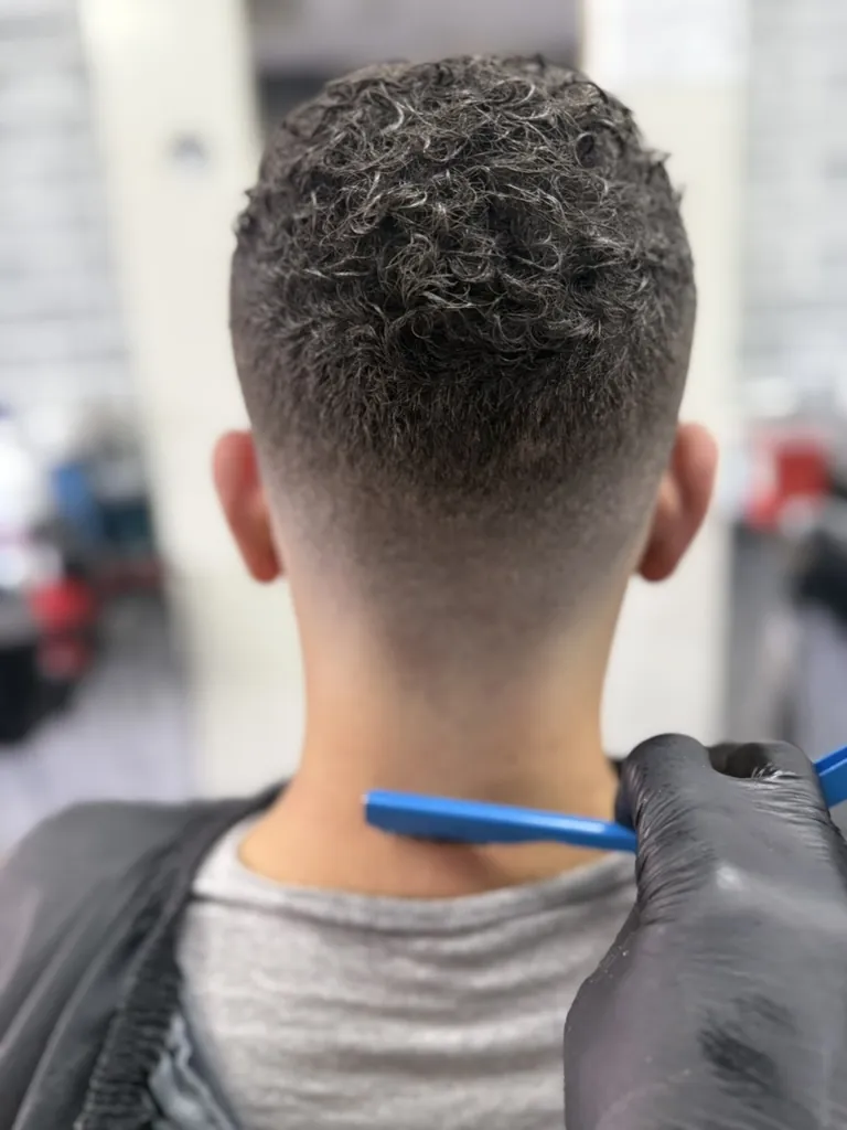 Back view of curly hair with a clean taper fade at a Denver barbershop near Aurora