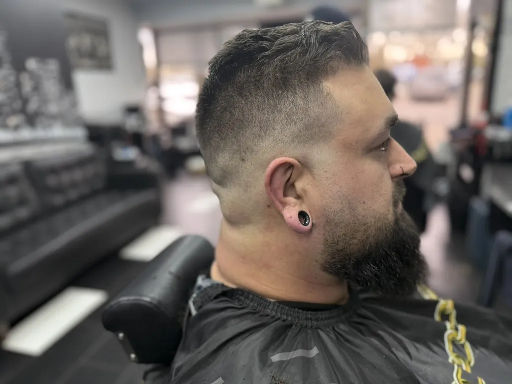 Man with a high fade haircut and full sculpted beard at Wise Guys Barbershop in Denver, Colorado