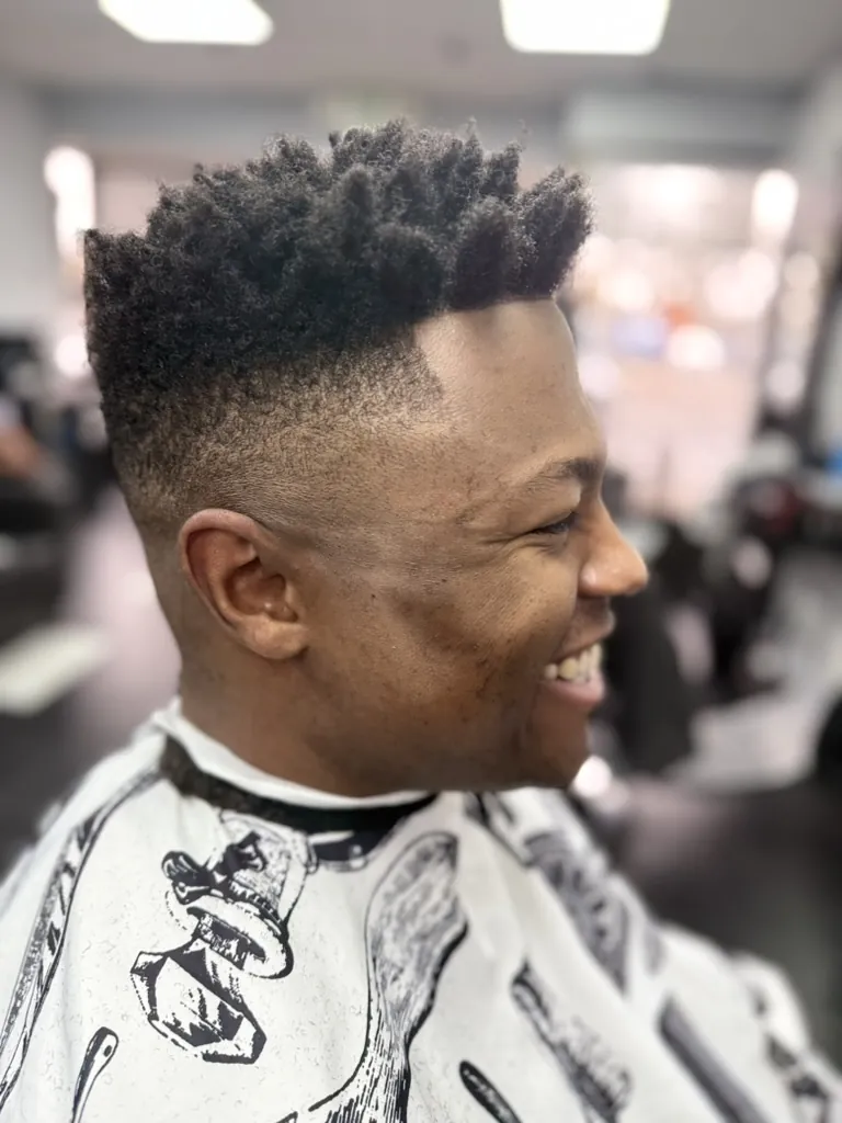 Man with a curly mohawk and burst fade haircut at Wise Guys Barbershop in Denver
