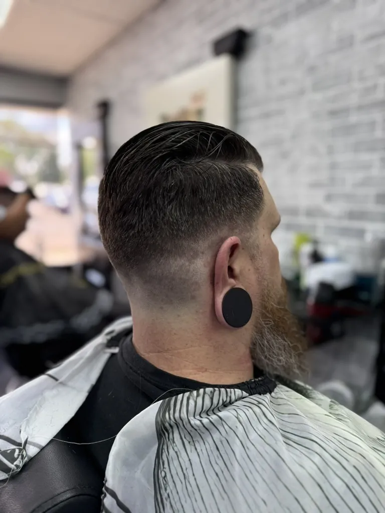 Slicked back taper fade haircut paired with a full beard at a Denver barbershop 80247